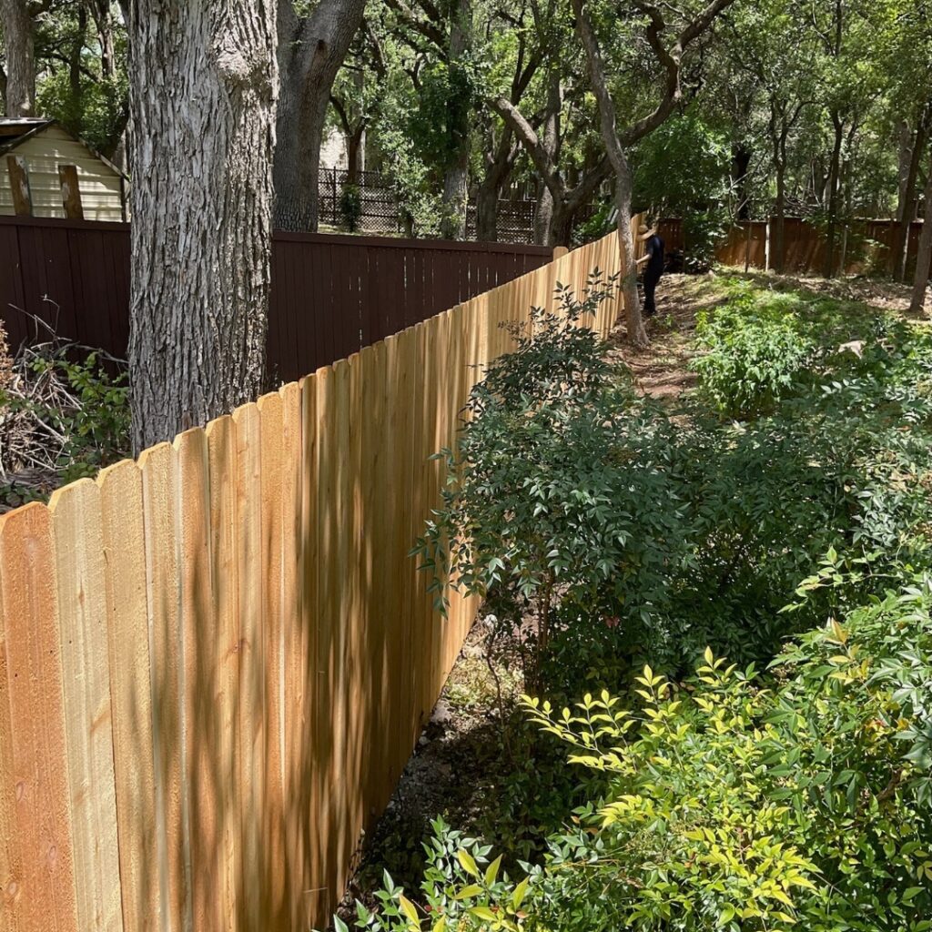Neatly aligned vertical picket fence providing structure and charm to a residential yard.