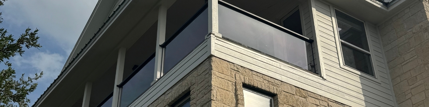 Finished plexiglass railing installed on a deck with crystal-clear acrylic panels and black framing.