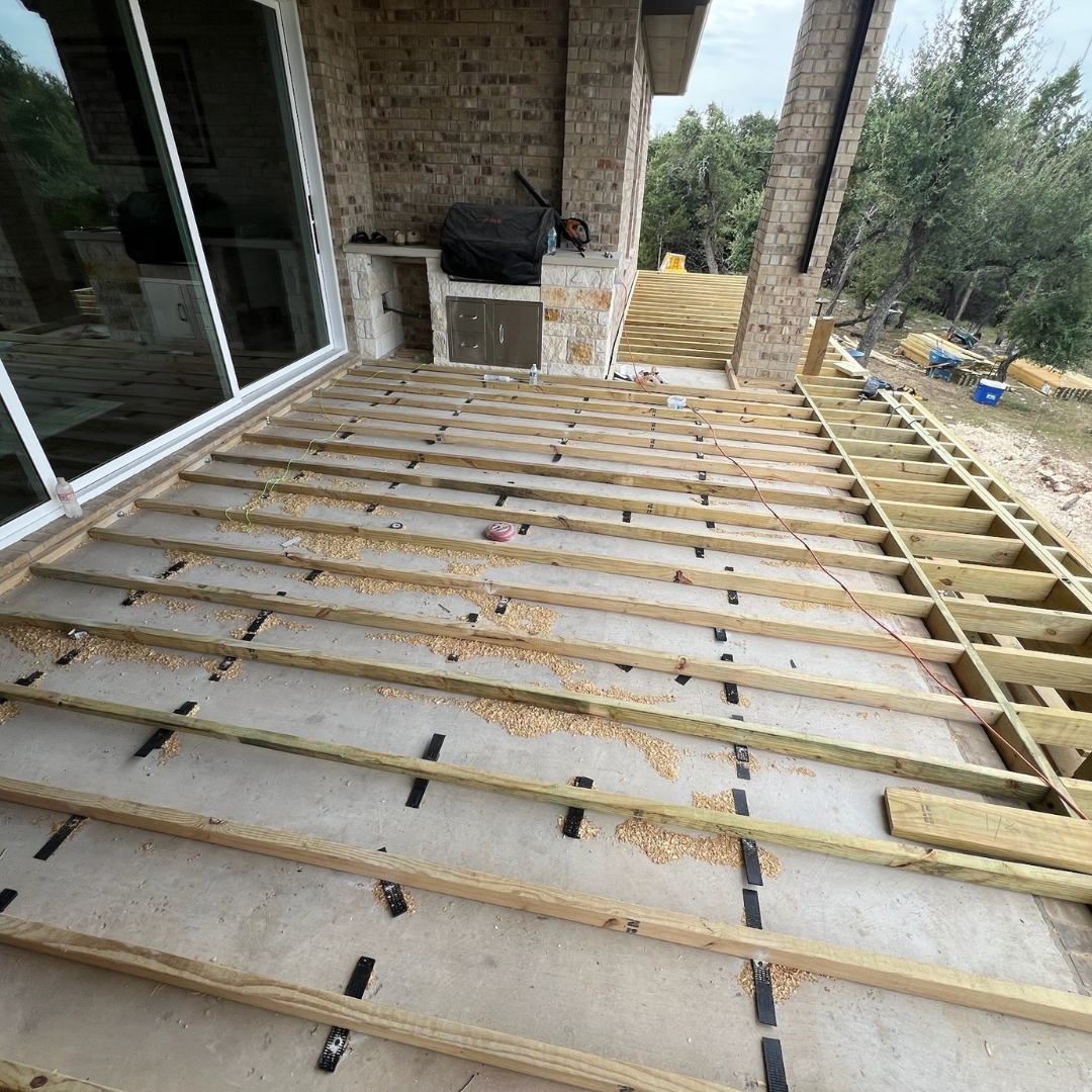 Progress view of deck project with materials, tools, and landscape lighting installation underway