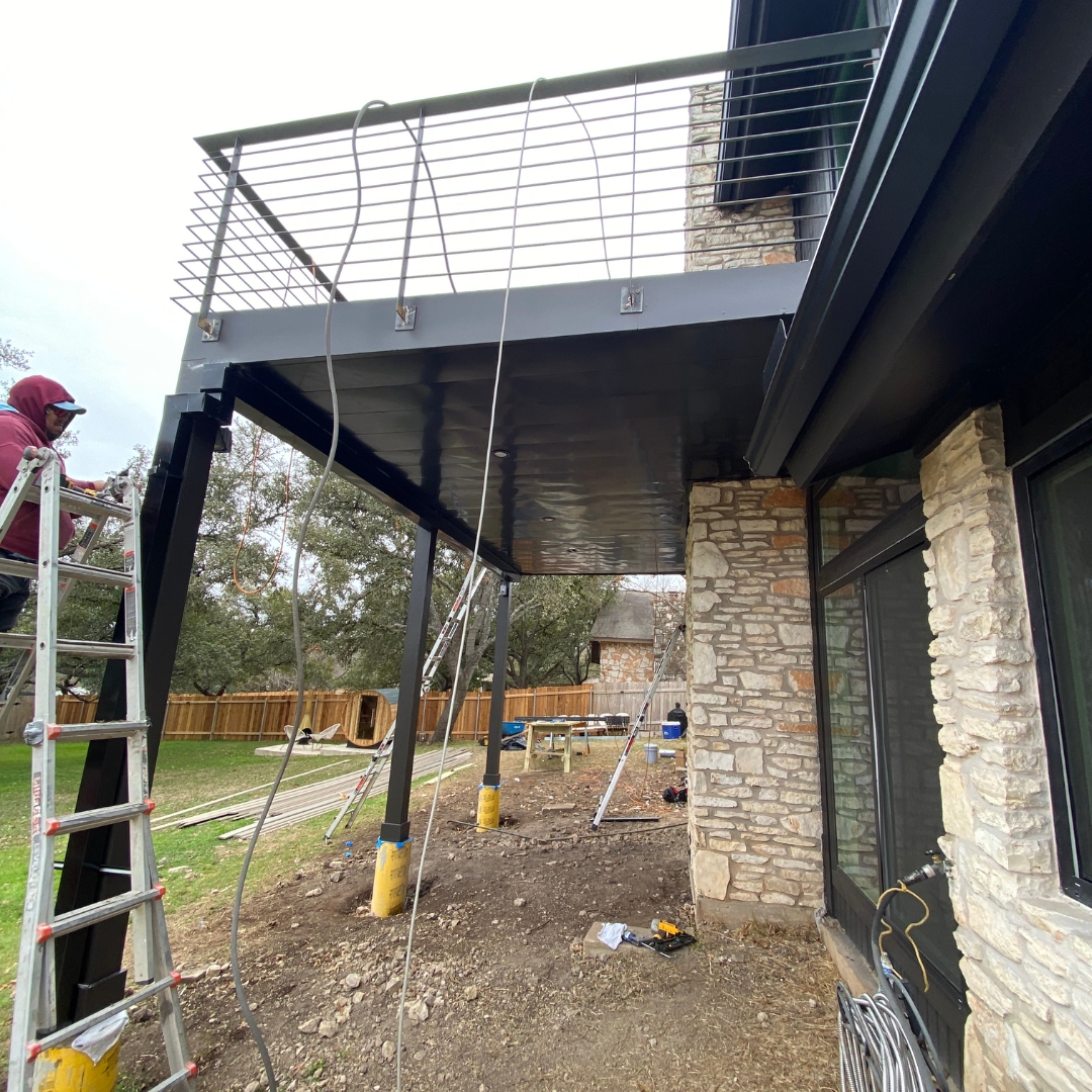 Mid-build view showing deck structure, metal balustrade posts, and soffit preparation