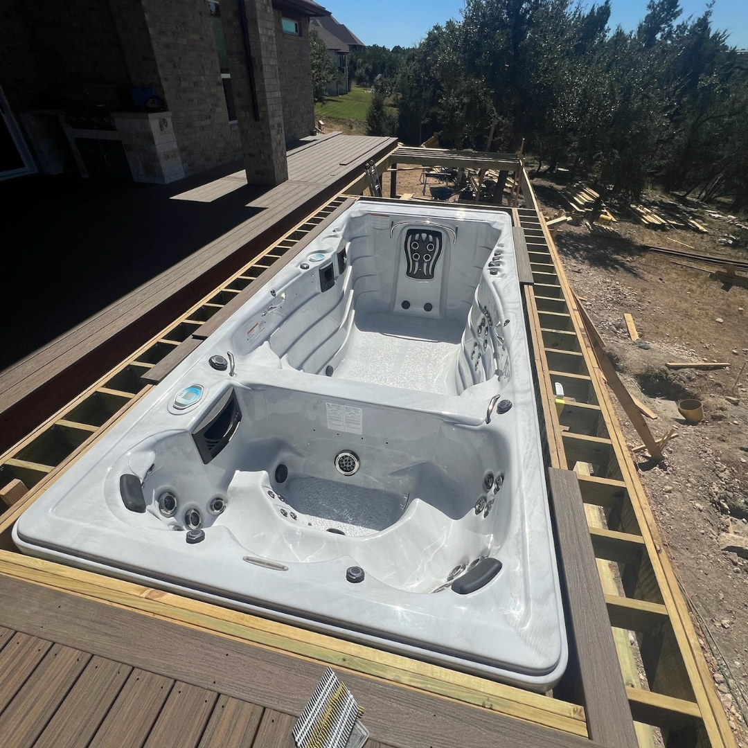 Mid-build phase showing partial decking, motorized cover setup, and electrical prep for lighting
