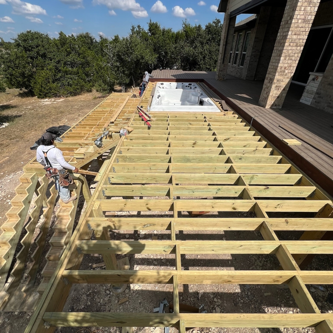 Progress view of deck project with materials, tools, and landscape lighting installation underway