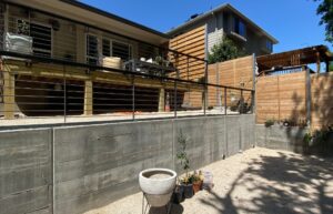 View of the custom deck with stairs connecting the upper and lower yard, featuring a sleek horizontal metal balustrade railing.
