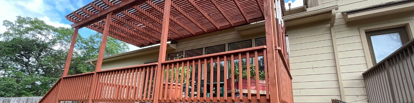 Fully stained pergola with rich red solid finish on rafters and shade bars.