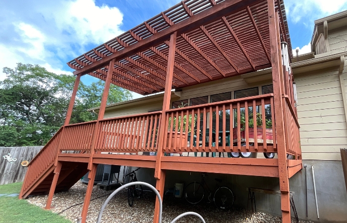 Fully stained pergola with rich red solid finish on rafters and shade bars.