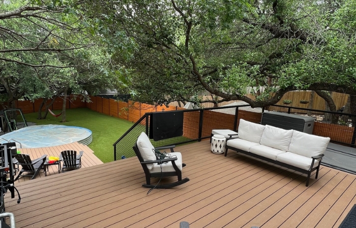 Two-level Trex Saddle Brown composite deck with custom bull panel steel railing and artificial turf inset.