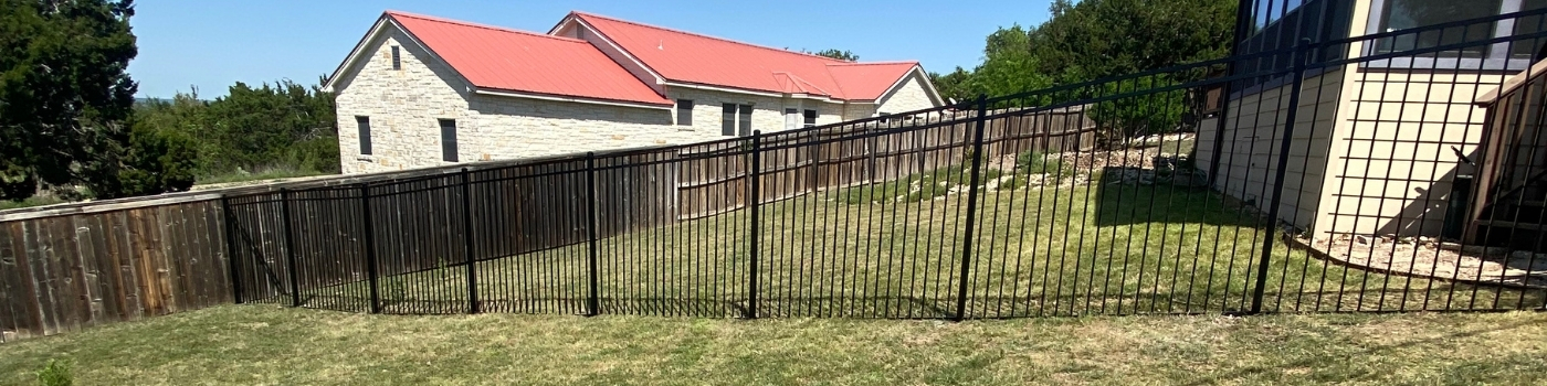 Newly installed ornamental iron fence with flat top and flat bottom.