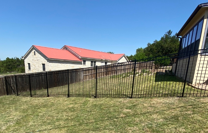 Newly installed ornamental iron fence with flat top and flat bottom.