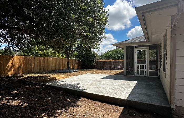 Wide view showing all outdoor features: concrete pad, hot tub area, and fire pit zone.