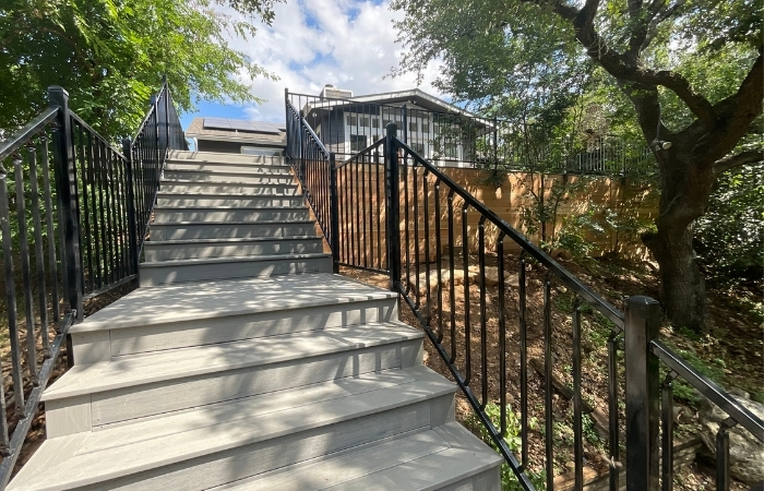 Custom residential deck installation featuring TimberTech Sea Salt Gray composite decking, ornamental iron railing, and new staircase construction.