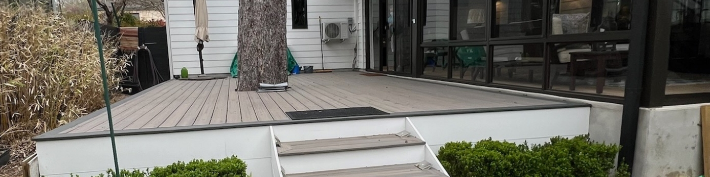 Completed Trex Rocky Harbor Deck with staircase and white fascia skirt in a finished outdoor patio.