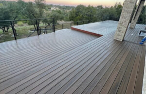 Installation of a Trex Toasted Sand composite deck with stainless steel cable railing, motorized deck cover, and integrated landscape lighting.
