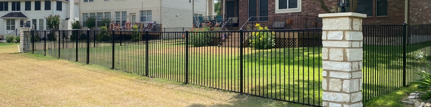 Completed ornamental iron fence framed by limestone block pillars.
