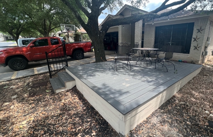 Trex Clamshell deck with a neatly painted wood skirt and limestone paver walkway.