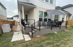 Installation of a Trex Enhance Rocky Harbor deck with ornamental iron railing, matching Trex skirting, and smooth, integrated deck stairs.