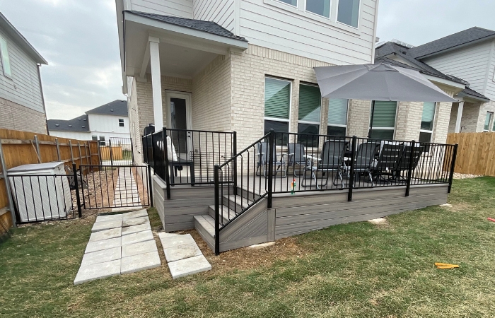 Installation of a Trex Enhance Rocky Harbor deck with ornamental iron railing, matching Trex skirting, and smooth, integrated deck stairs.