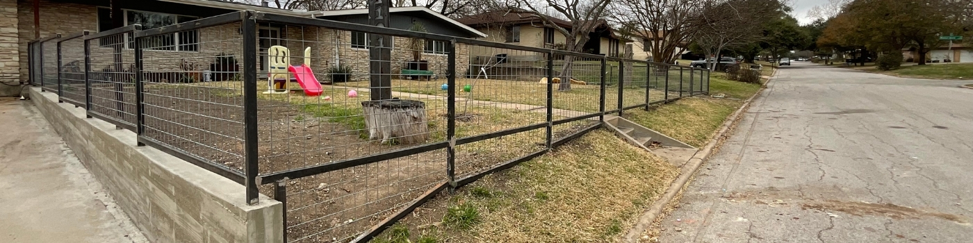 Concrete retaining wall with a 4-foot bull panel fence on top, enclosing the front yard.