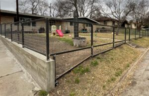 Concrete retaining wall with a 4-foot bull panel fence on top, enclosing the front yard.