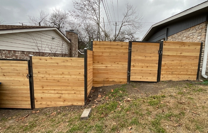 Horizontal cedar fence with steel posts installed around a residential backyard.
