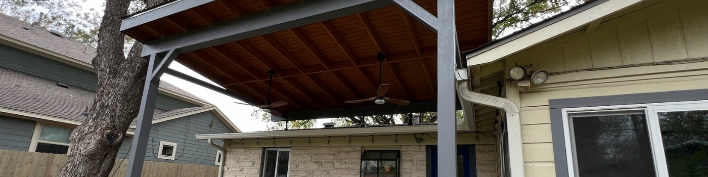 Completed patio cover with exposed rafters and T1-11 ceiling, providing shade over the new deck.