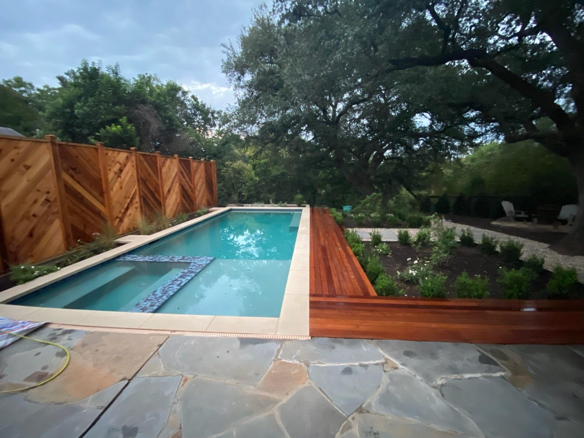 A backyard featuring a pool surrounded by a cinder block custom fence.